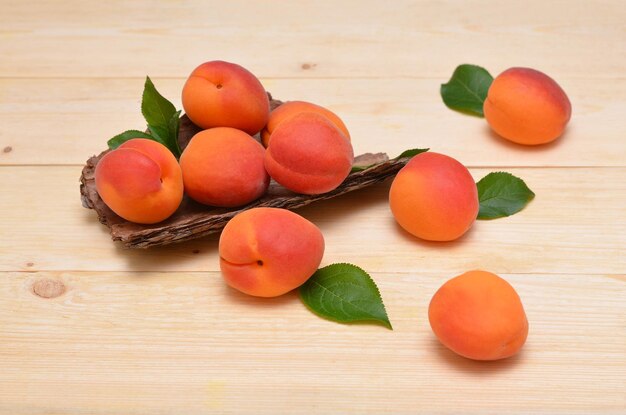 Fresh apricots with leaves on wooden background