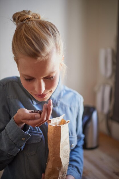 コーヒー豆の新鮮な香りキッチンで新鮮なコーヒー豆の匂いを嗅ぐ若い女性