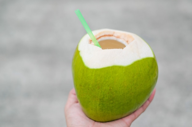사진 신선한 향기로운 코코넛 주스, 코코넛 과일 손에 흐림 배경.