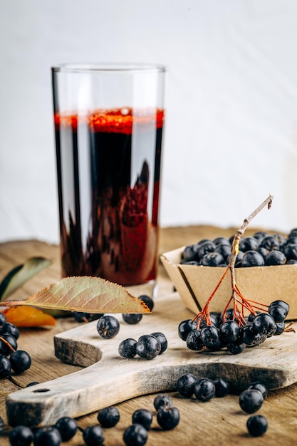 Fresh aronia berries and berry juice in a glass.