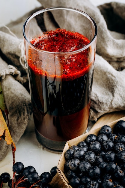 Fresh aronia berries and berry juice in a glass.