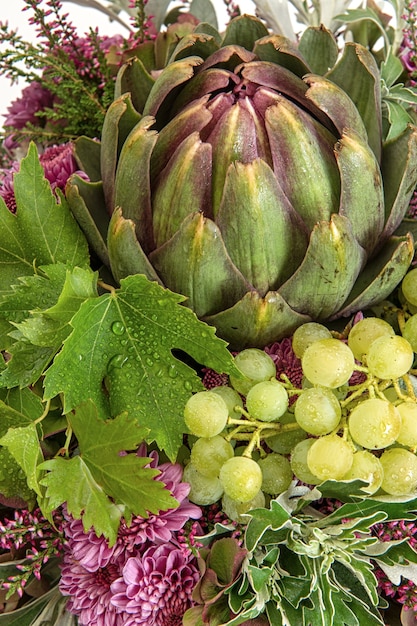 Fresh artichoke with grapes berries and leaves. autumn composition