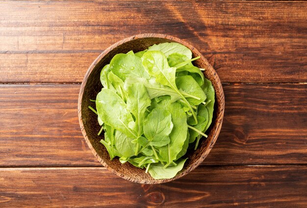 Fresh arugula leaves in brown bowl top view