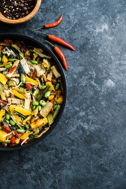 Fresh asian vegetables mix, thai wok in a black pan on the black