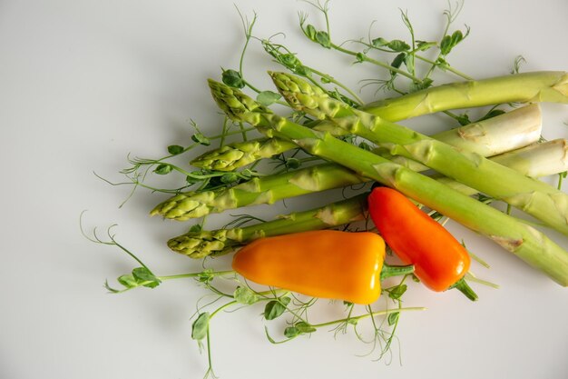 Fresh asparagus and bell pepper with peas on white background