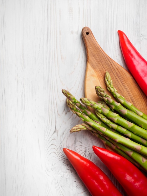 Fresh asparagus and red ramiro peppers on olive wood cutting board