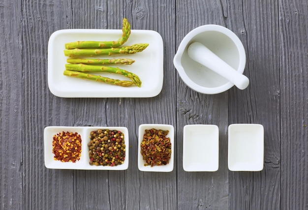 Fresh asparagus served on white plate with rustic wooden table background top view