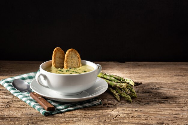 Fresh asparagus soup on wooden table