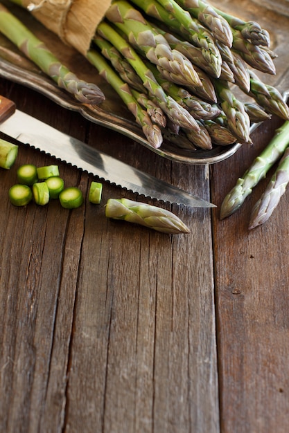 Fresh asparagus with knife on a wooden table close up with copy space