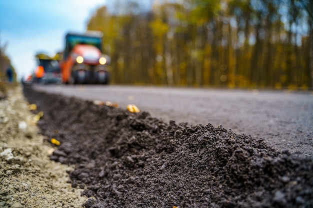 Fresh asphalt on highway construction site. Industrial pavement machine laying.