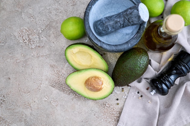 Avocado fresco tagliato a metà e mortaio di marmo su tavolo di cemento grigio