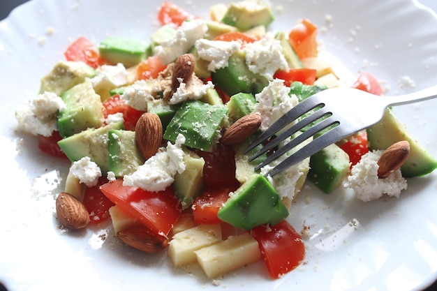 Foto avocado fresco deliziosa insalata mediterranea con pomodorini e mandorle e parmigiano feta