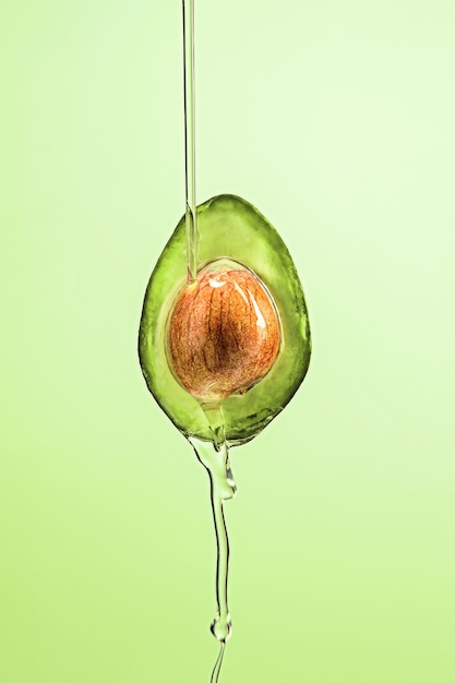 Fresh avocado and oil on green background