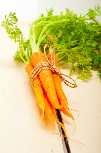 Fresh baby carrots bunch tied with rope on a rustic table