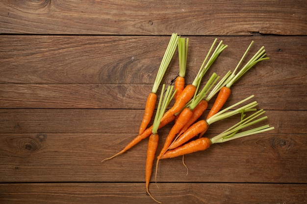 Fresh baby carrots on wooden cutting board and wooden background