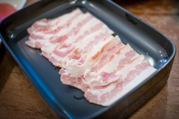 Fresh bacon raw sliced was served for Sukiyaki and Shabu or Yakiniku   restaurant which it put on white plate.