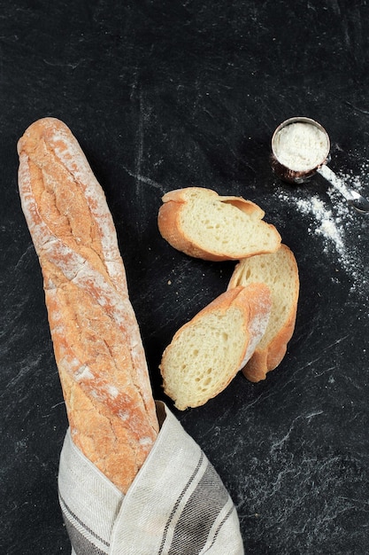 Foto pane baguette fresco su fondo di legno francese fatto in casa due pagnotte e fette di baguette