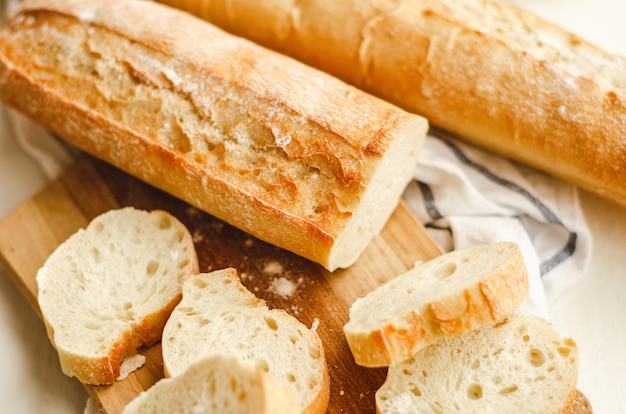 Fresh baguettes with a crisp crust chopped on cutting board