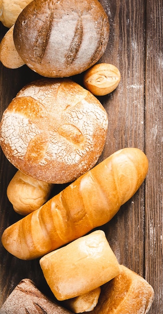 Fresh baked bread with a golden crust loaf buns white rye on a rustic wooden background with sil rustic Flat layout