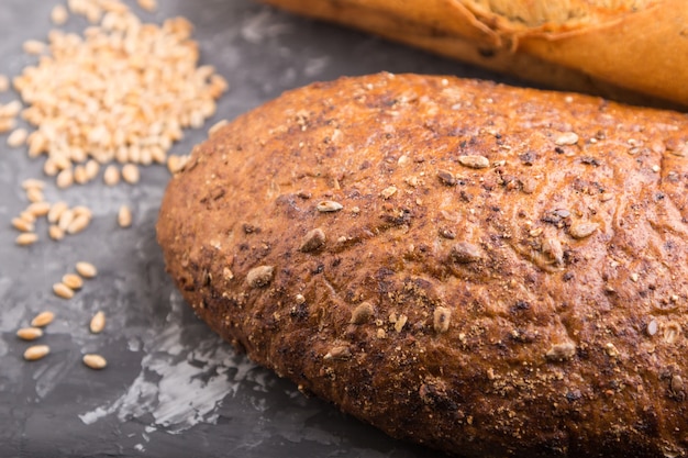 Fresh baked bread with grains on a black concrete surface. side view, selective focus.