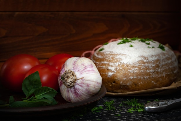 Fresh baked bread with tomatoes and garlic with basil on a dark wooden background