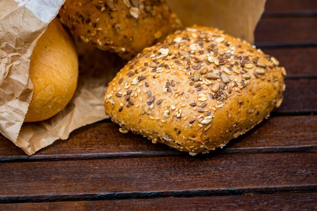 Fresh baked bread wrapped in paper, on wooden.