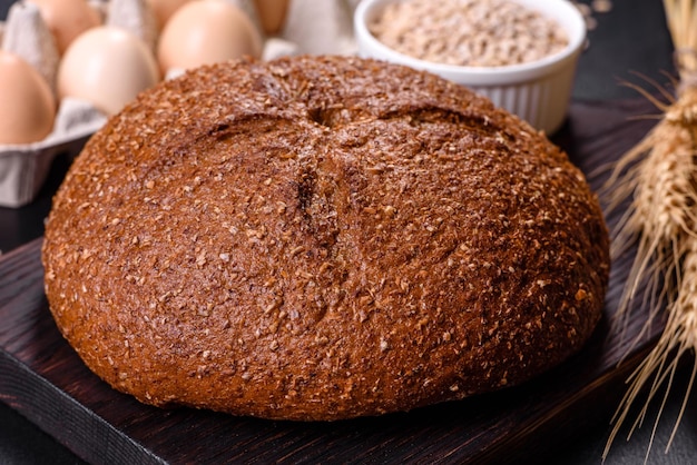 Fresh baked brown bread with ears and grains of wheat