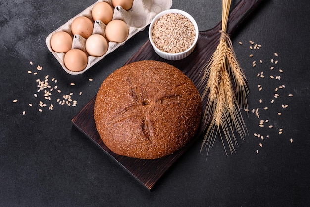 Свежеиспеченный черный хлеб с ушами и зернами пшеницы