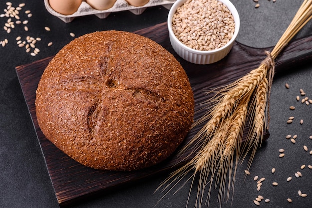 Свежеиспеченный черный хлеб с ушами и зернами пшеницы