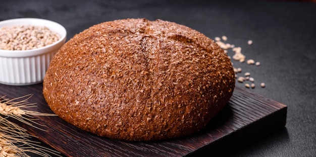 Fresh baked brown bread with ears and grains of wheat