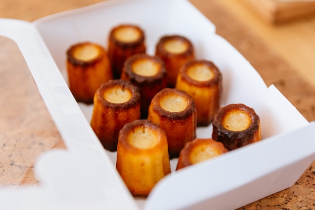 흰 종이 상자 안에 신선한 구운 Canelés.