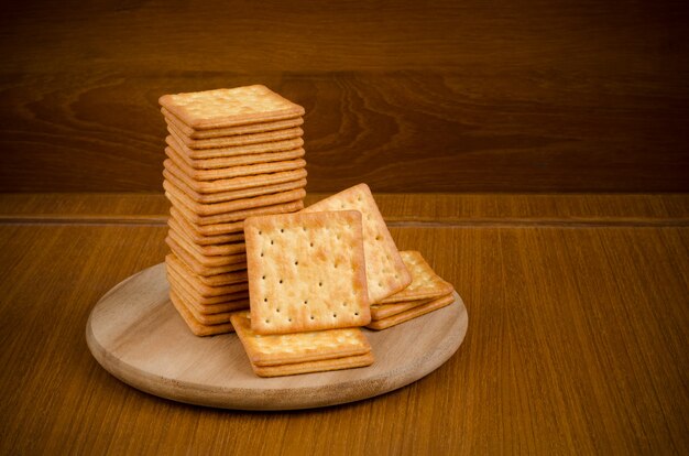 Fresh baked cream crackers in stacks over wooden cutting circle board