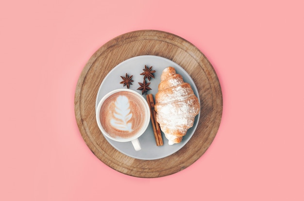 Fresh baked croissant with coffee cup and latte art, cinnamon