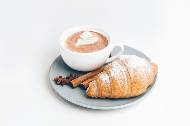 コーヒーカップとラテアートの焼きたてのクロワッサン