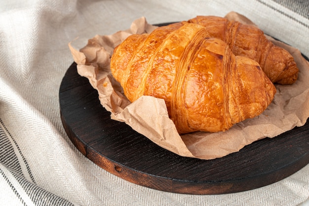 Fresh baked croissant on wooden table close up