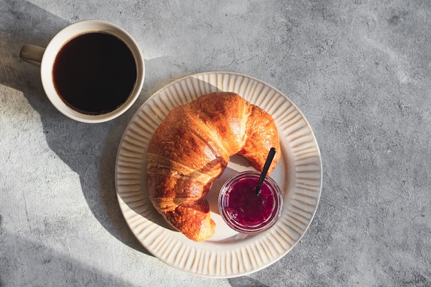 Fresh Baked Croissants with coffee espresso jam and butter on gray stone background