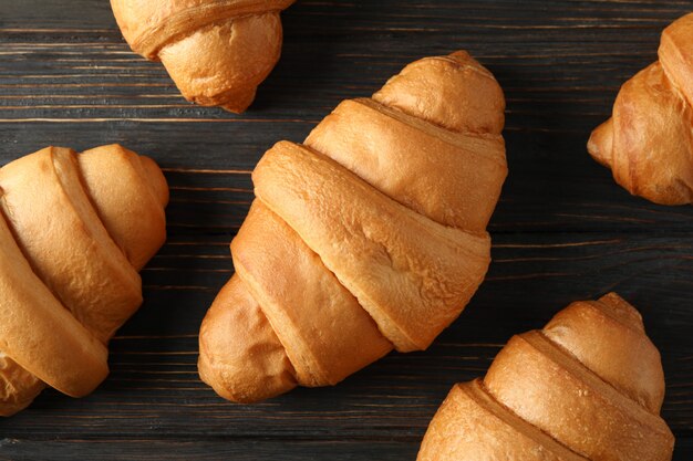 Fresh baked croissants on wooden background, top view