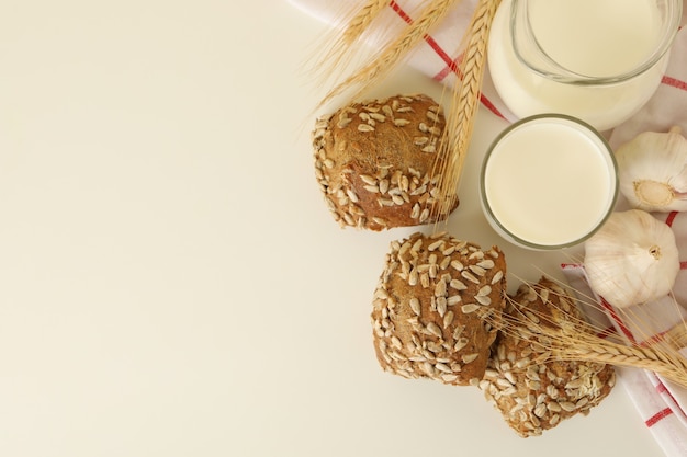 Fresh baked garlic buns and milk on white table