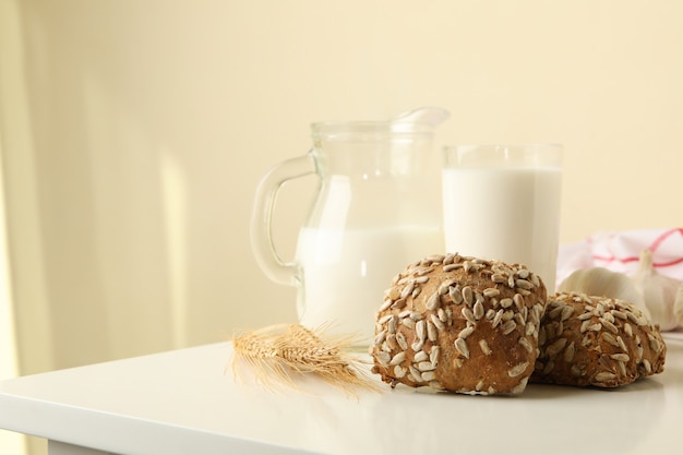 Fresh baked garlic buns and milk on white table