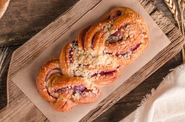 Fresh baked goods - delicious wicker bun with filling on wooden background