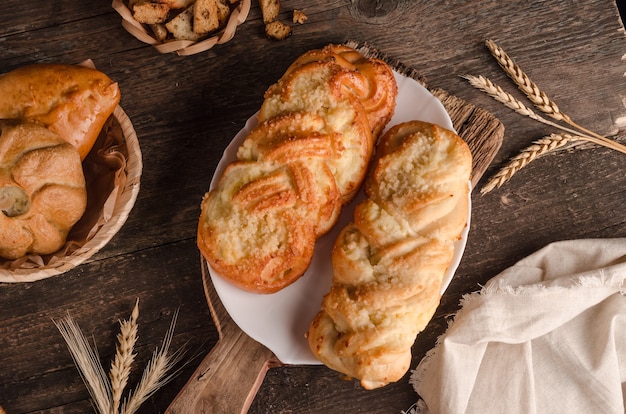 Fresh baked goods - delicious wicker buns with filling on wooden background