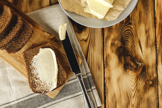 Fresh baked loaf of bread with butter bar on wooden table