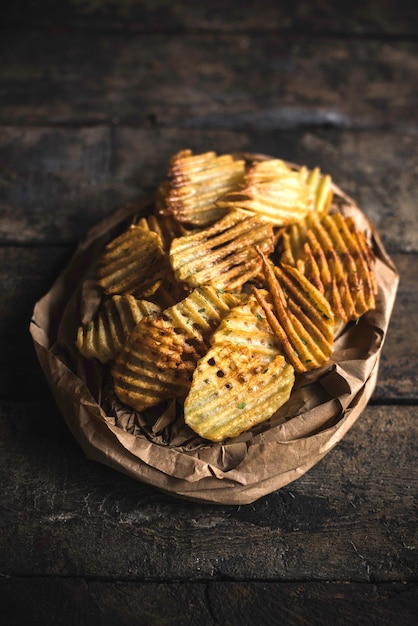 Fresh baked potatoes chips served on the wooden tableselective focus