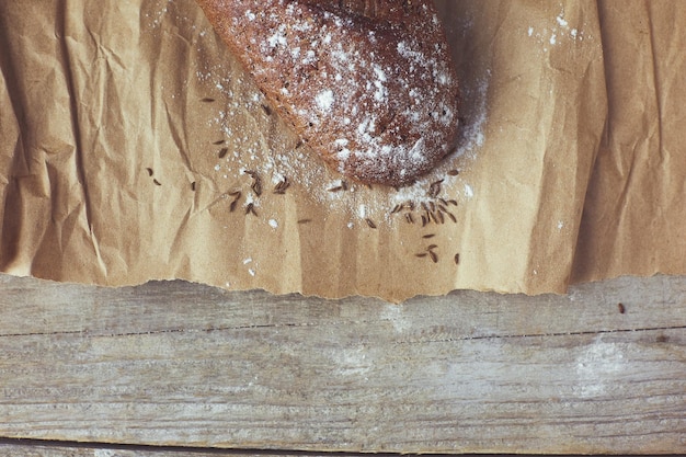 Fresh baked rustic bread loaves in paper bags on dark wood background