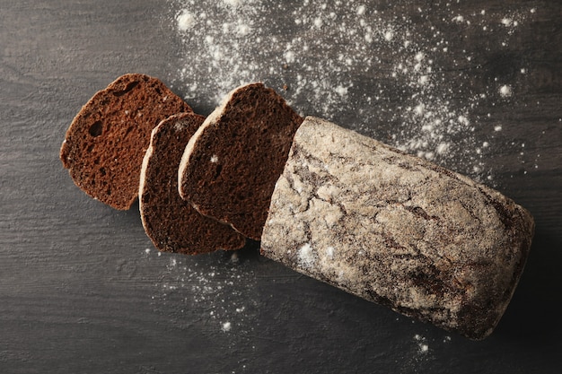 Fresh baked rye bread and flour on black background