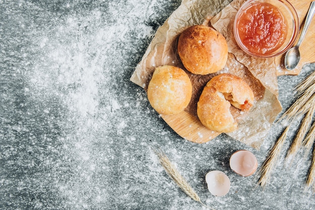 Fresh baked yeast buns filled with apple jam on gray background with flour.