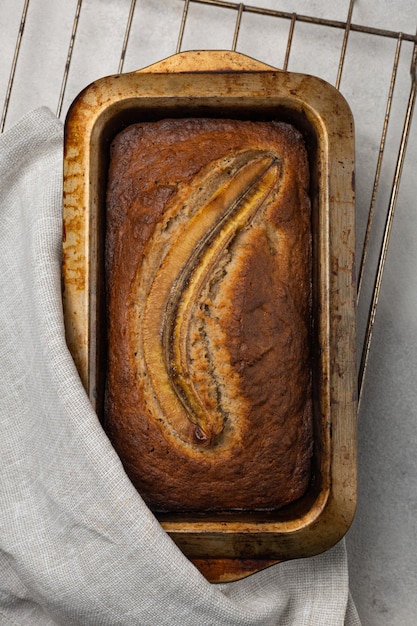 Fresh banana bread in a baking dish on a wire rack in the oven on a light background