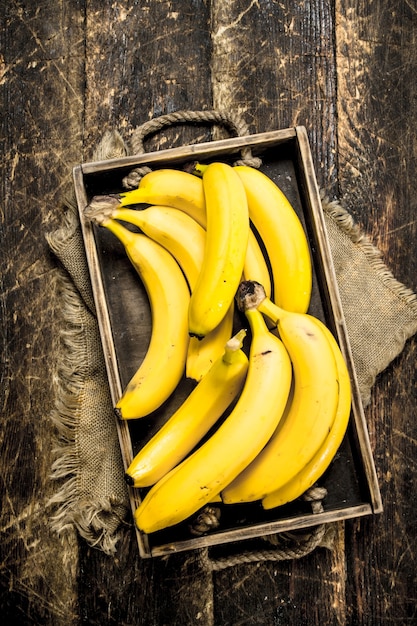 Banane fresche su un vecchio vassoio. su uno sfondo di legno.