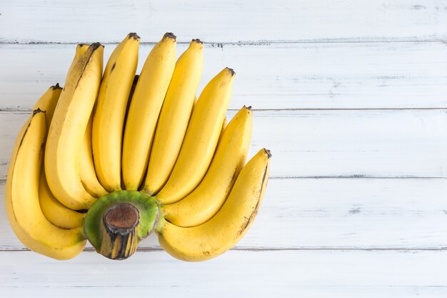 Fresh bananas on white wooden background