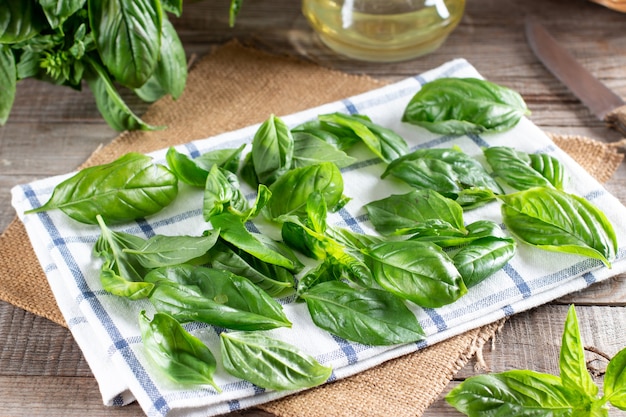 Fresh basil leaves on a napkin on a wooden table. Drying leaves before freezing. Frozen food concept